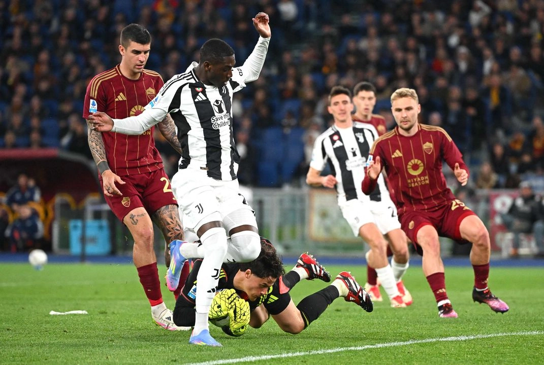 El delantero francés #20 de la Juventus, Kolo Muani (izq.), lucha por el balón con el portero serbio #99 de la Roma, Mile Svilar (centro), durante el partido de la Serie A italiana entre la AS Roma y la Juventus en el Estadio Olímpico de Roma el 6 de abril de 2025. Foto