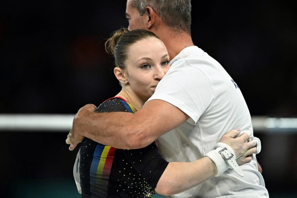 La rumana Ana Barbosu reacciona con su entrenador después de competir en la prueba de barras asimétricas de la clasificación femenina de gimnasia artística durante los Juegos Olímpicos de París 2024 en el Bercy Arena de París, el 28 de julio de 2024. Foto Afp
