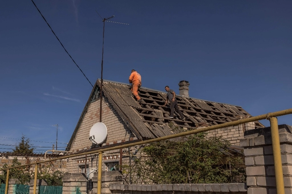 Hombres reparan una vivienda dañada por ataques rusos en la región ucrania de Jersón, el 30 de octubre de 2023. Foto Afp