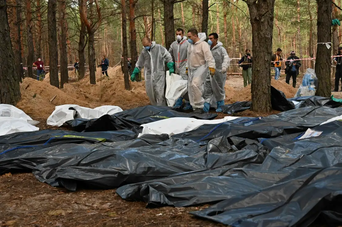 Médicos forenses colocaron ayer en bolsas algunos de los 445 cuerpos que fueron enterrados en un bosque en las afueras de la ciudad de Izium. Foto Afp