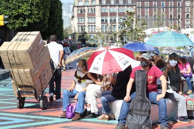 Personas utilizan sombrillas para resguardarse del sol en el Centro Histórico de la CDMX. Foto Roberto García 