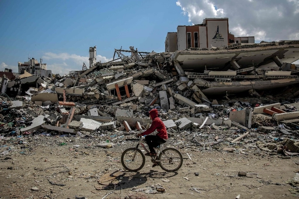 Un hombre pasa en bicicleta por la Universidad de al-Aqsa, arrasada por un bombardeo israelí en la ciudad de Gaza el 15 de febrero de 2024. Foto Afp
