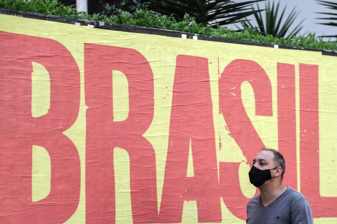 Un hombre camina frente a un cartel, en Sao Paulo, Brasil. Foto Xinhua / Archivo 