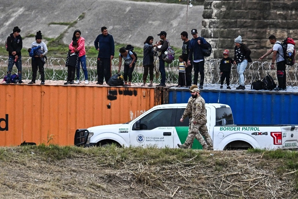 Migrantes sobre contenedores tras cruzar la frontera desde México a Eagle Pass, Texas, el 22 de diciembre de 2023. Foto Afp