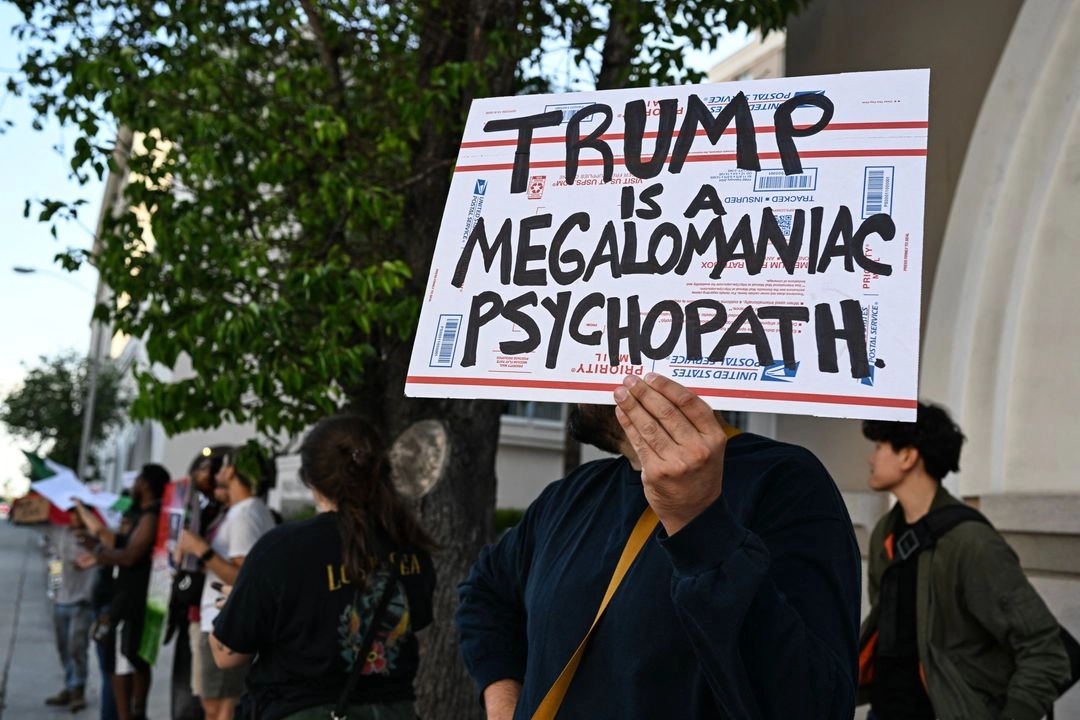 Un manifestante sostiene un cartel durante una manifestación en respuesta a las operaciones federales de inmigración en Las Fuentes Plaza en Pasadena, California, el 13 de junio de 2025.