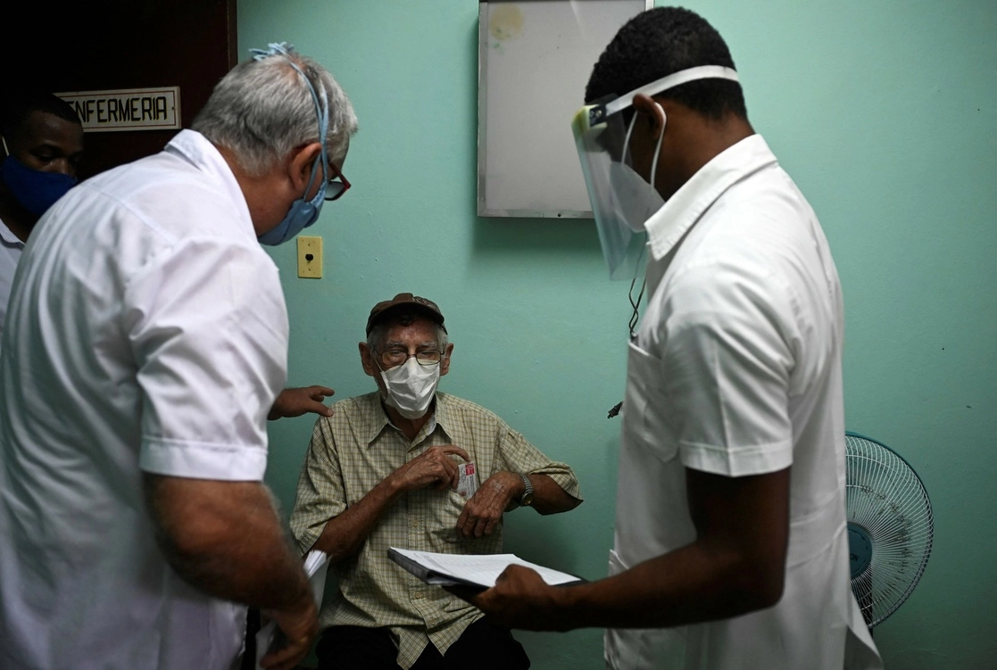 Personal de salud habla con un hombre mayor antes de inocularlo con la candidata a vacuna cubana contra el Covid-19 Abdala. La isla inició su campaña de prevención contra el coronavirus el miércoles con dos de sus cinco antígenos aspirantes a ser vacunas. Foto Afp