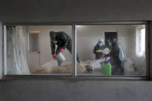 Clérigos con ropa protectora preparan el cuerpo de un hombre que murió de Covid-19 para un funeral en un cementerio en las afueras de la ciudad de Ghaemshahr, en el norte de Irán. Foto Ap