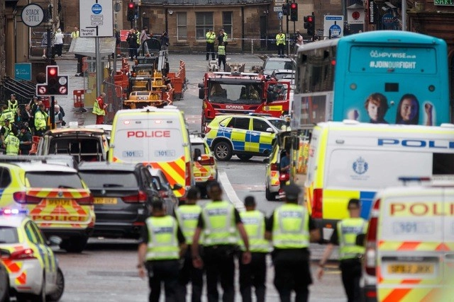 Agentes y elementos del servicio de emergencia resguardan la escena donde ocurrió un ataque, en el centro de Glasgow. Foto Afp