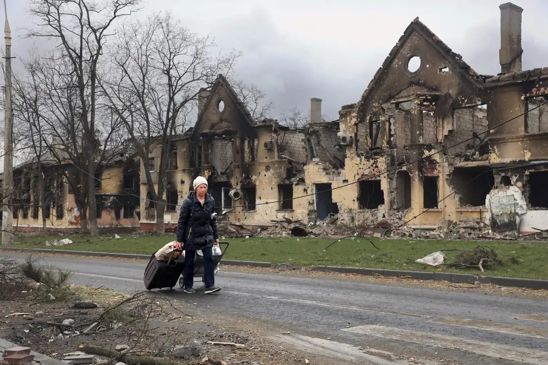 Una mujer camina frente a casas dañadas durante los combates en Mariúpol, en el territorio que ahora está bajo el control del Gobierno de la República Popular de Donetsk, al este de Ucrania, el pasado 8 de abril de 2022. Foto Ap