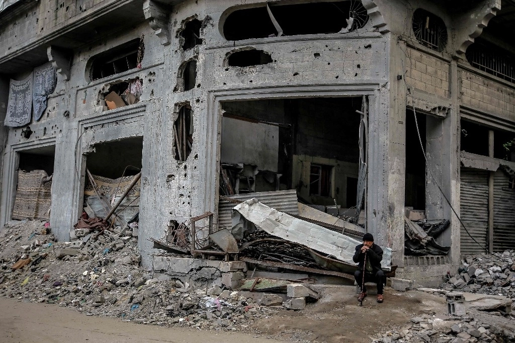 Un hombre palestino sentado afuera de un edificio destruido por el bombardeo israelí en la ciudad de Gaza, el 3 de marzo de 2024. Foto Afp
