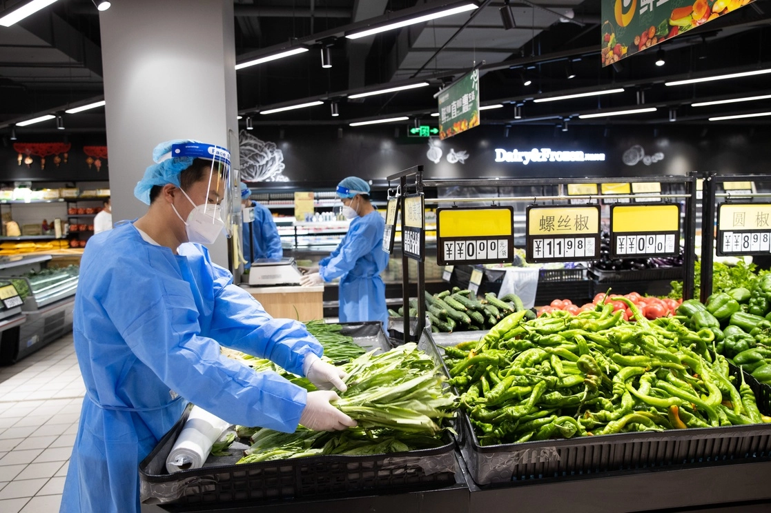 Trabajadores arreglan mercancías en un supermercado, en el distrito de Xuhui de Shanghai, en el este de China. Foto Xinhua