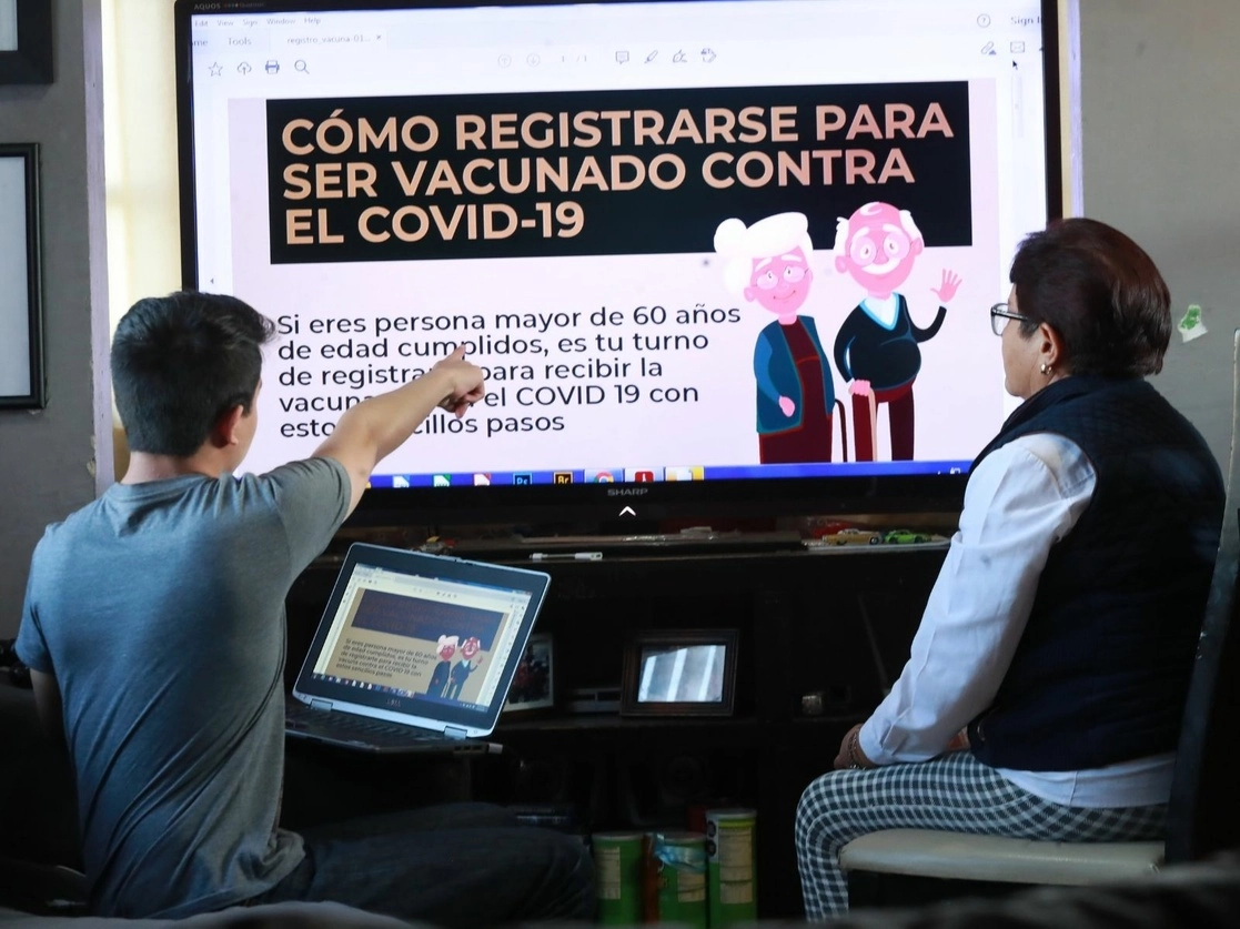 El nieto de una mujer le explica cómo registrarse para completar el registro para ser vacunada, el 2 de febrero de 2021. Foto Luis Castillo 
