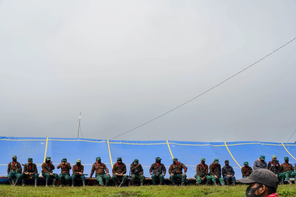 Milicianos y milicianas sentadas frente a uno de sus campamentos durante el Encuentro de Resistencias y Rebeldías del EZLN.