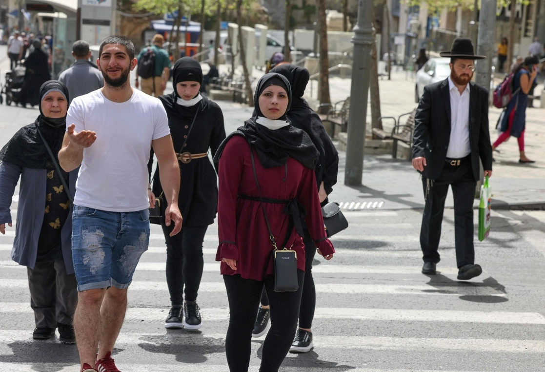 Hombres y mujeres caminan por las calles de Jerusalén sin cubrebocas por primera vez en un año. Foto Afp 