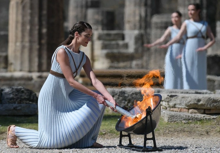 La actriz griega Xanthi Georgiou, en el papel de la Suma Sacerdotisa, enciende la antorcha olímpica durante la ceremonia en el sitio cerrado de la Antigua Olimpia, lugar de nacimiento de las antiguas Olimpiadas en el sur de Grecia, el jueves 12 de marzo de 2020. Foto AP / Thanassis Stavrakis