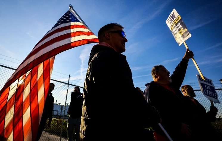 Los miembros del UAW Dan Schlieman, con bandera, y Brad Geer trabajan en el piquete durante una huelga este martes. Foto Ap