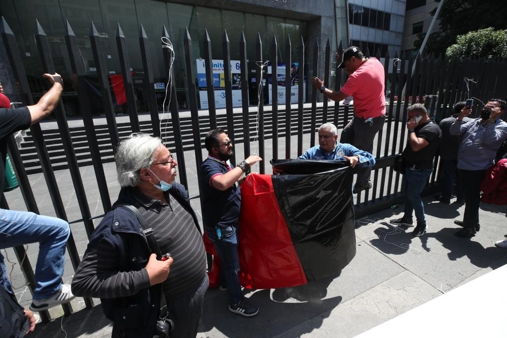 Trabajadores de Telmex retiran las banderas de huelga que ayer fueron colocadas en las oficinas centrales de esa empresa, ubicada en la alcaldía Cuauhtémoc, el 22 de julio de 2022. Foto José Antonio López