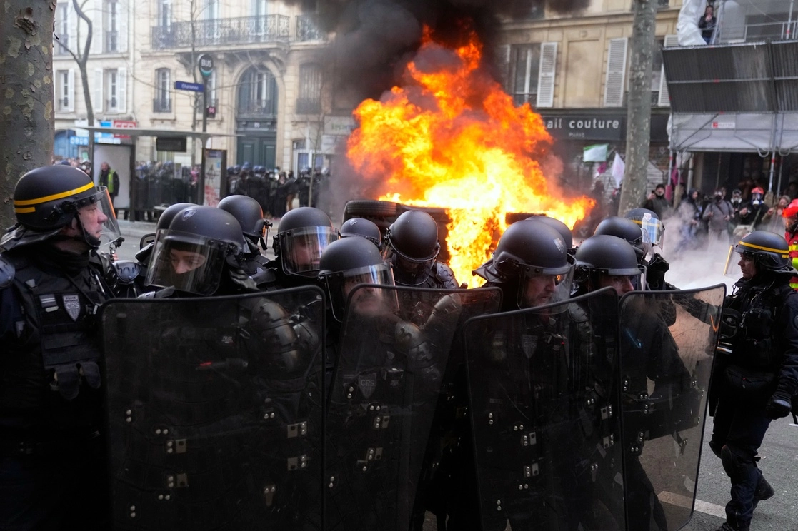 Policías antidisturbios junto a un automóvil en llamas durante enfrentamientos en una manifestación contra los planes para retrasar la edad de jubilación de Francia, este sábado. Foto Ap