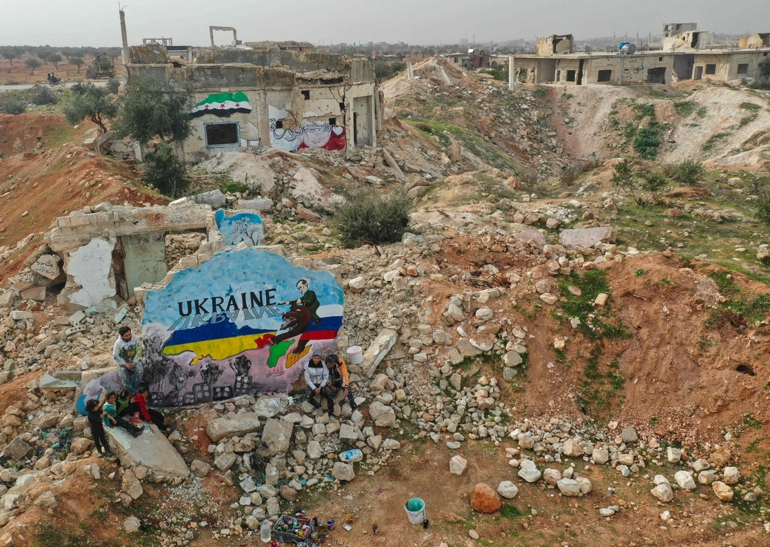 Un mural en medio de ruinas, que representa los colores de las banderas rusa y ucrania, fue pintado por artistas sirios para protestar contra la operación militar de Rusia en Ucrania, en la ciudad rebelde de Binnish, en la provincia noroccidental de Idlib, Siria, el 24 de febrero de 2022. Foto Afp

