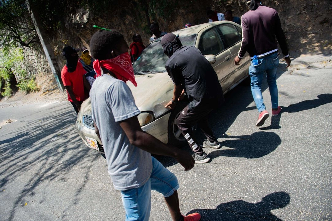 Manifestantes rodean un automóvil mientras bloquean el paso en Puerto Príncipe, Haití, el 27 de marzo de 2025. Foto 
