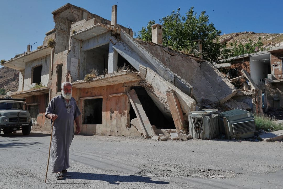 Un hombre pasa junto a una casa destruida durante la guerra civil siria en la aldea de Beit Jin, en el sur de Siria, donde las tropas israelíes realizaron una incursión antes del amanecer, el 12 de junio de 2025. Foto
