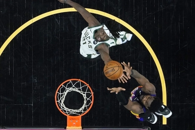 Deandre Ayton de los Soles de Phoenix (der) y el guardia de los Bucks de Milwaukee, Jrue Holiday (c) disputan un rebote durante el juego. Foto Ap