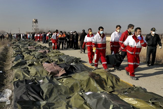 Rescatistas cargan el cuerpo de unas de las víctimas del accidente del avión ucranio en Teherán, en imagen de ayer. Foto Ap 