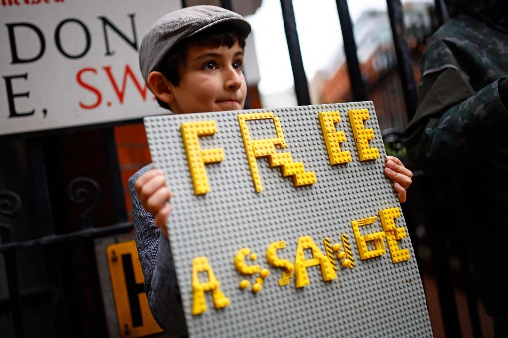 Un niño sostiene un cartel de apoyo para Julian Assange, hecho con piezas de Lego, afuera de la embajada ecuatoriana en Londres. Foto Afp 