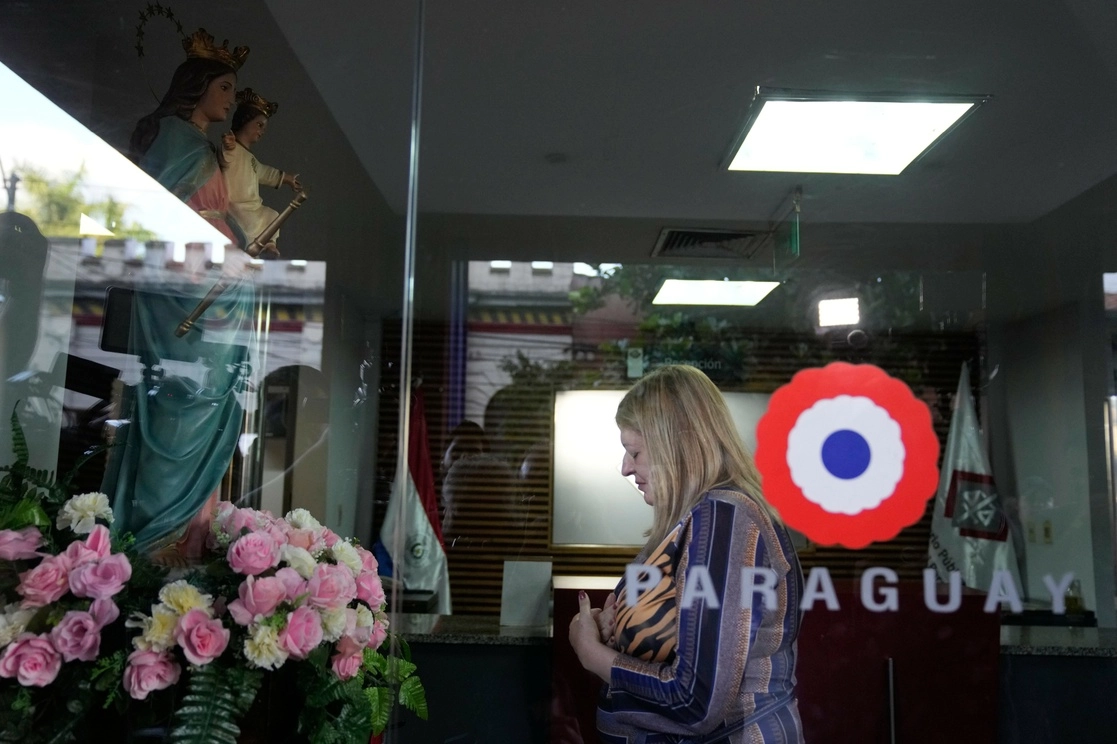 Sandra Quiñonez, de la Fiscalía de Paraguay, reza frente a una figura de la Virgen María en la entrada de su oficina después de enterarse del asesinato durante su luna de miel en Colombia del fiscal paraguayo Marcelo Pecci, ayer. Foto Ap