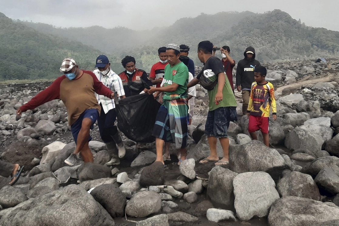 Rescatistas y pobladores trasladan los restos de una víctima de la erupción del volcán Semeru en Indonesia, el 7 de diciembre de 2021. Foto Ap
