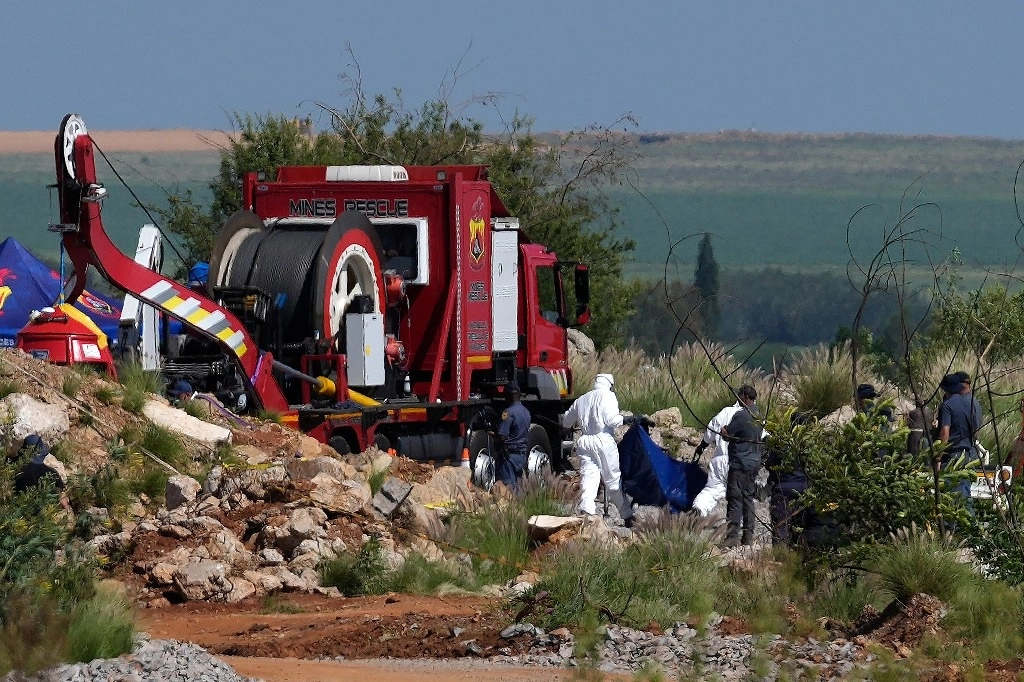 Trabajadores del servicio forense llevan restos en bolsas azules para cadáveres durante una operación para rescatar a los mineros de debajo de la tierra en una mina de oro abandonada en Stilfontein, Sudáfrica, el 14 de enero de 2025. Foto Ap
