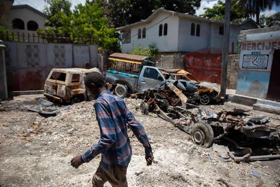 Un hombre pasa junto a vehículos carbonizados y abandonados en el barrio de La Plaine de Puerto Príncipe, Haití. Foto Ap