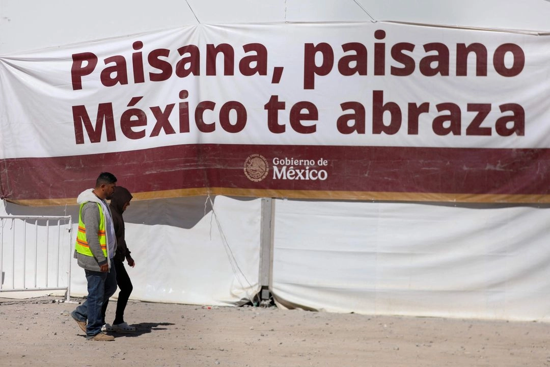 Un empleado federal mexicano camina con un migrante mexicano deportado de Estados Unidos al Centro de Atención a Migrantes en el Punto, Ciudad Juárez, Chihuahua. 