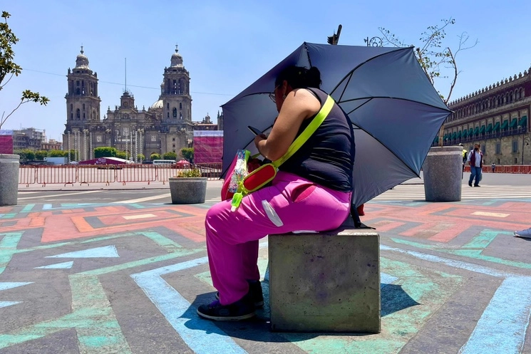 Una mujer se cubre con una sombrilla ante la intensidad de los rayos del sol, en el Zócalo capitalino, el 15 de junio de 2023. Foto Luis Castillo