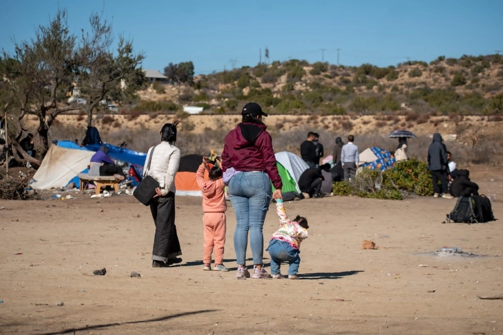 Una familia de migrantes observa hacia territorio estadunidense en el nuevo campamento instalado ayer en Tecate, Baja California. Foto ‘La Jornada Baja California’