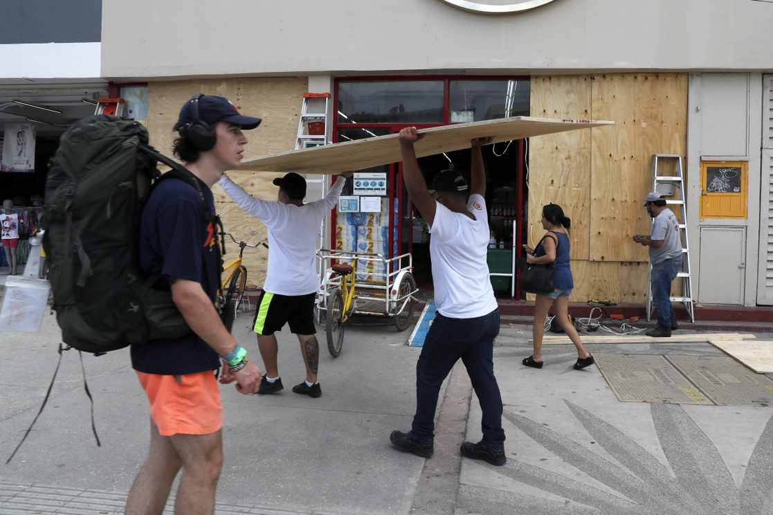Trabajadores de un supermercado en Tulum, Quintana Roo, instalaron en las ventanas protecciones para evitar daños ante la llegada del huracán ‘Grace’, que impactó esta localidad, el 18 de agosto de 2021. Foto Ap