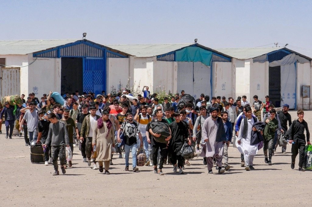 Refugiados afganos caminan con sus pertenencias después de ser deportados de Irán en la frontera Islam Qala entre Afganistán e Irán, en la provincia occidental de Herat, el 30 de mayo de 2024. Foto Afp