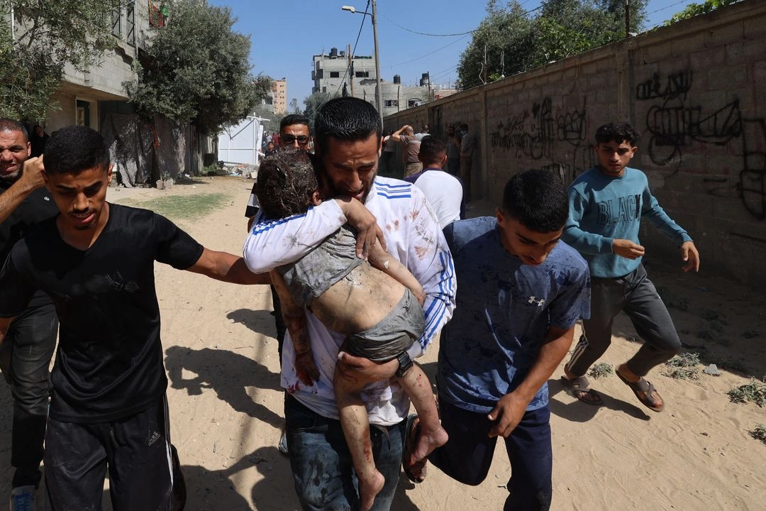 Un padre lleva a su hijo herido en el campamento de Al-Bureij, en el centro de la Franja de Gaza, después de que la zona fuera atacada por un ataque israelí, el 17 de junio de 2025.