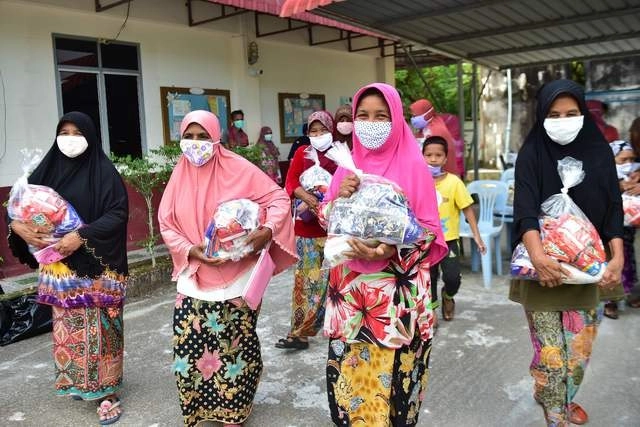 Mujeres con cubrebocas después de recoger donaciones de comida en Tailandia. Foto Afp 