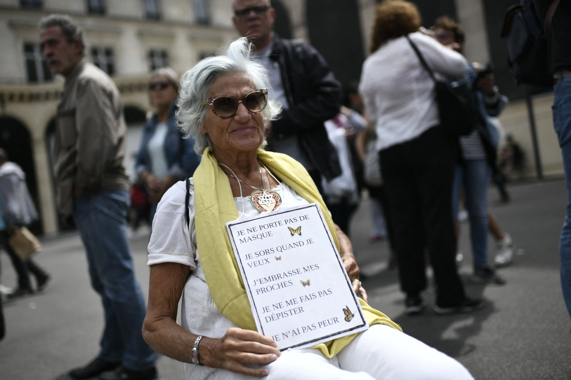 Una mujer mayor se manifiesta contra la vacuna del coronavirus, con una pancarta en la que se lee "No uso cubrebocas. Salgo cuando quiero. Beso a mis seres queridos. No em hago pruebas. No tengo miedo", en París, el 5 de agosto de 2021. Foto Afp 