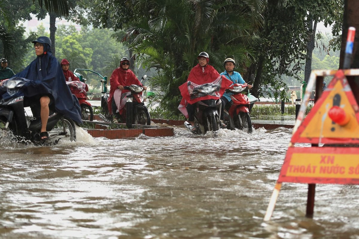 La gente conduce motocicletas en una calle inundada causada por el tifón Kajiki en Hanoi, Vietnam, el 26 de agosto de 2025.