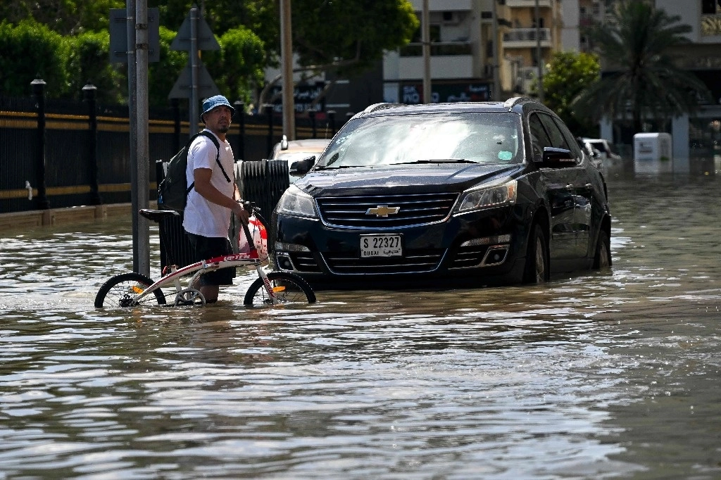 Un hombre cruza una inundada calle en Sharjah, tras las torrenciales lluvias, el 18 de abril de 2024. Foto Afp