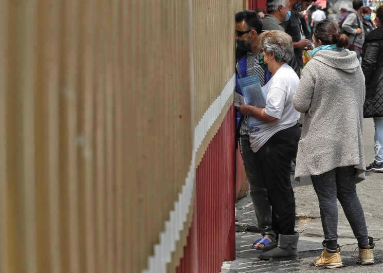 Personas esperan fuera del Hospital General a recibir información de sus familiares que se encuentran internados por Covid-19. Foto Marco Peláez
