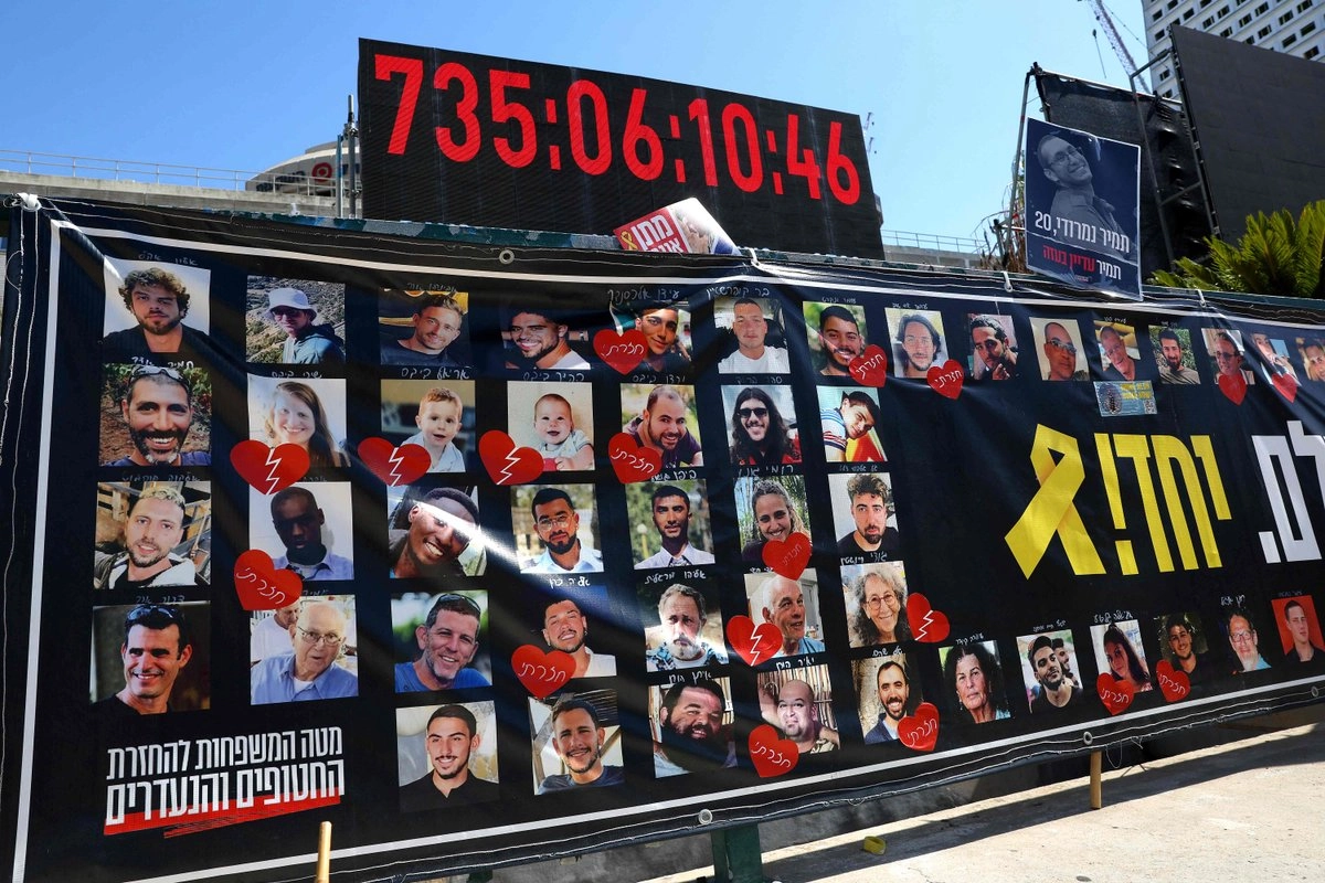 Retratos de rehenes israelíes retenidos por militantes palestinos en la Franja de Gaza desde los ataques del 7 de octubre de 2023 se muestran bajo un reloj digital que indica los días, horas y minutos que han permanecido en cautiverio, frente al Museo de Arte de Tel Aviv, conocido como la "Plaza de los Rehenes" en Tel Aviv, Israel, el 11 de octubre de 2025. 