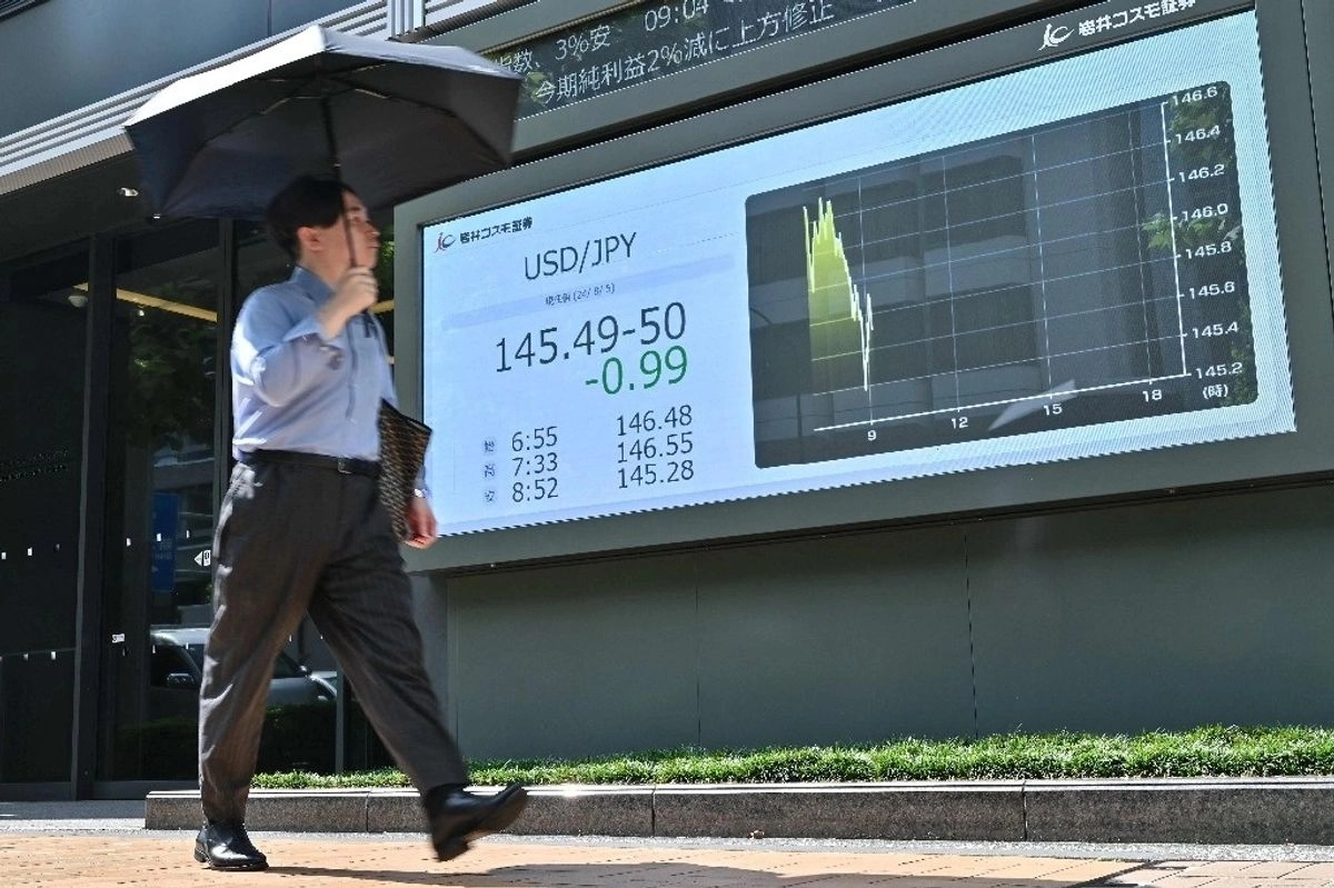 Un peatón pasa junto a un cartel que muestra el tipo de cambio entre el dólar estadunidense y el yen japonés, a lo largo de una calle de Tokio, en imagen de archivo. Foto