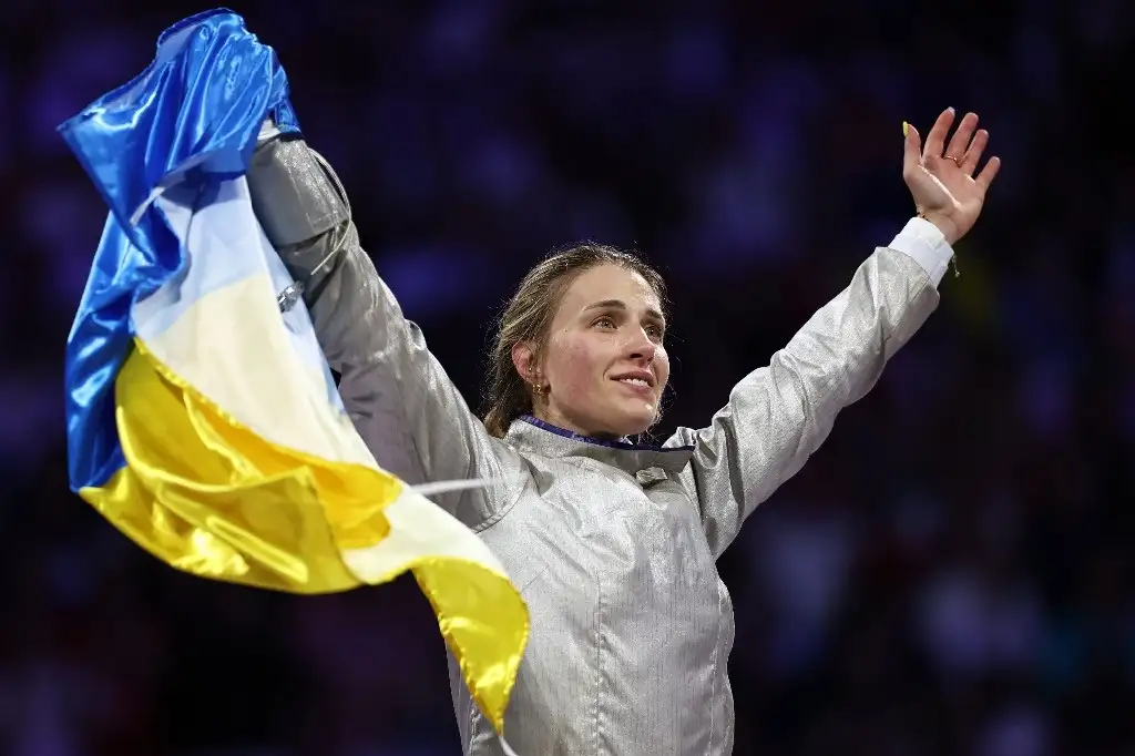 La ucrania Olga Kharlan celebra con la bandera de su país en la mano la victoria en la final de esgrima femenil, dentro de la modalidad de sable por equipos. Foto Afp   