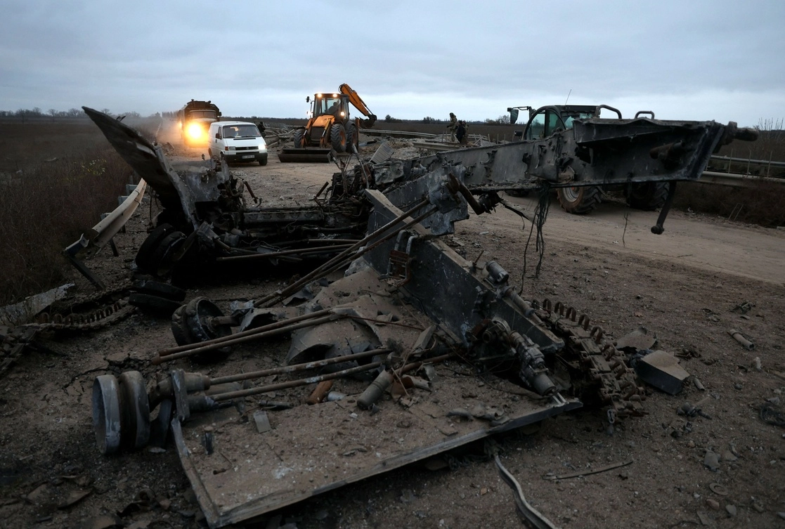 Automóviles y camiones pasan junto a un vehículo militar destruido en la carretera de la región de Kherson el 13 de noviembre de 2022, en medio de la invasión rusa de Ucrania.  Foto AFP