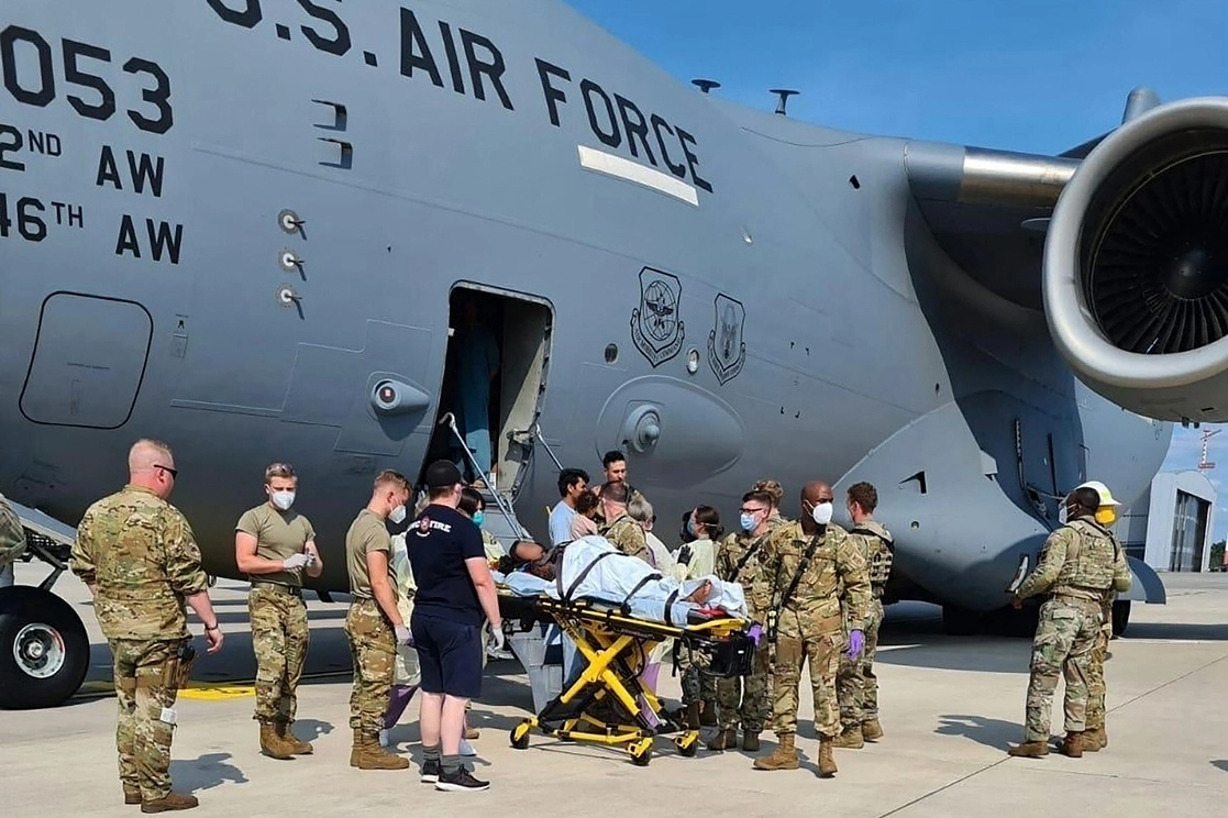 En esta imagen, cortesía de la Fuerza Aérea de Estados Unidos, personal del 86 Grupo Médico ayuda a una madre afgana y a su familia a salir del avión C-17 en el que dio a luz la mujer, procedente de Afganistán. La nave aterrizó en la base militar estadunidense de Ramstein. Foto vía Afp