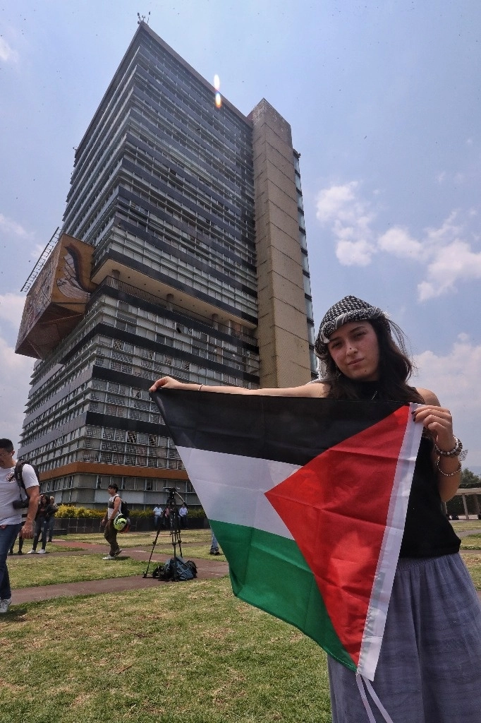 Universitaria sostiene la bandera de Palestina. Al fondo, la torre de Rectoría de la UNAM. Foto Marco Peláez 