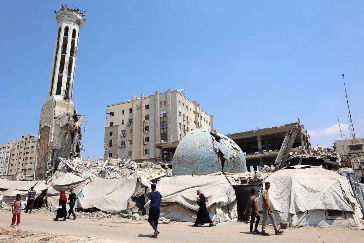 Palestinos caminan frente a la mezquita destruida de Abu Khudra en la ciudad de Gaza el 18 de agosto de 2025. 
